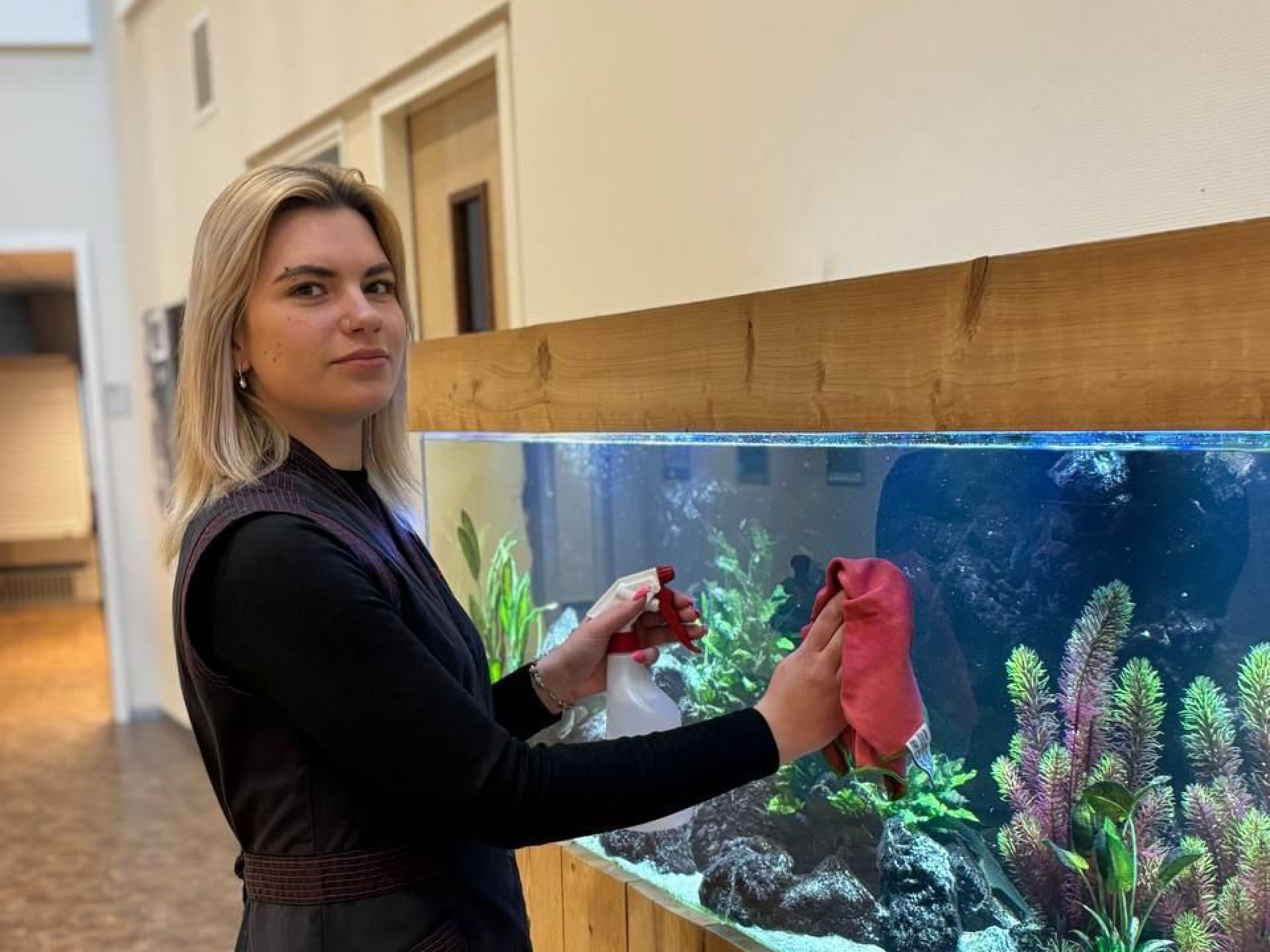 Vrouw die een aquarium schoonmaakt in een gang.