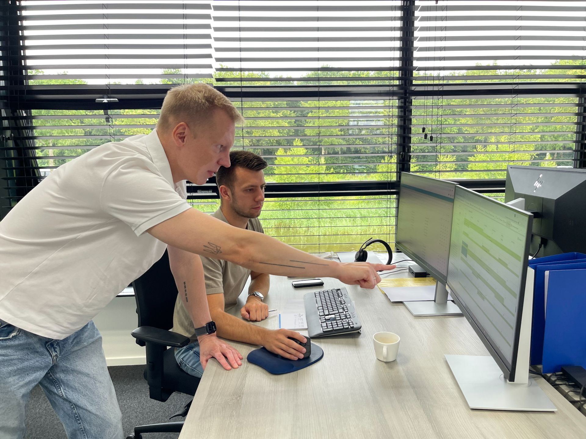 Twee mannen werken samen achter een computer in een kantoor.