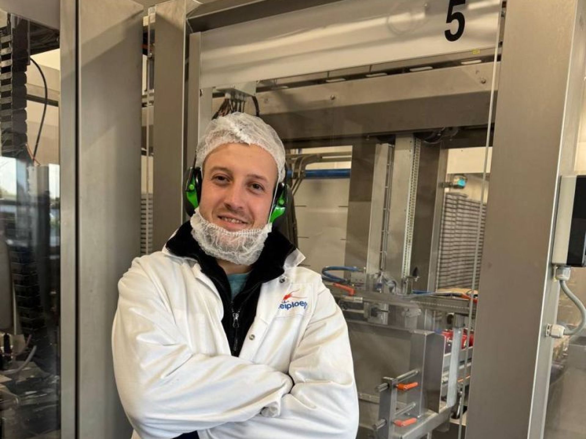 Een persoon in een witte laboratoriumjas staat in een fabriek.