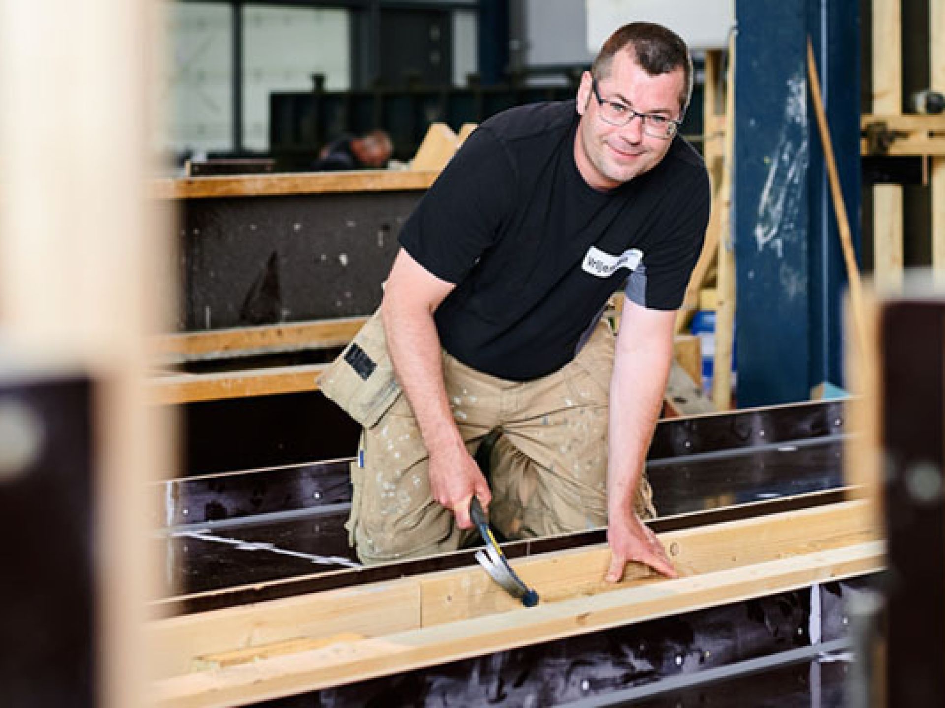 Een timmerman werkt in een werkplaats met een hamer.